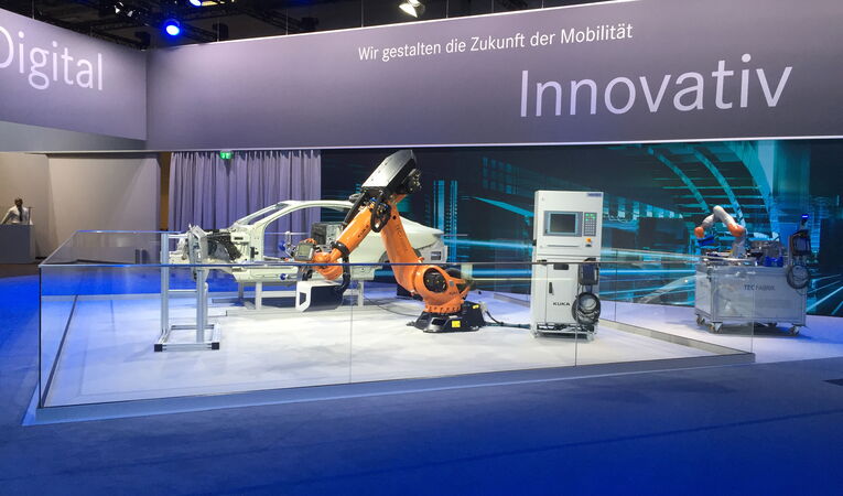 Daimler TecFabrik LeanFit Robotiksystem auf einer Fachmesse mit KUKA-Cobot und Fahrzeugkarosserie. Das mehrfach ausgezeichnete Montagesystem erhielt den iF Design Award sowie den Focus Open Silver Award.